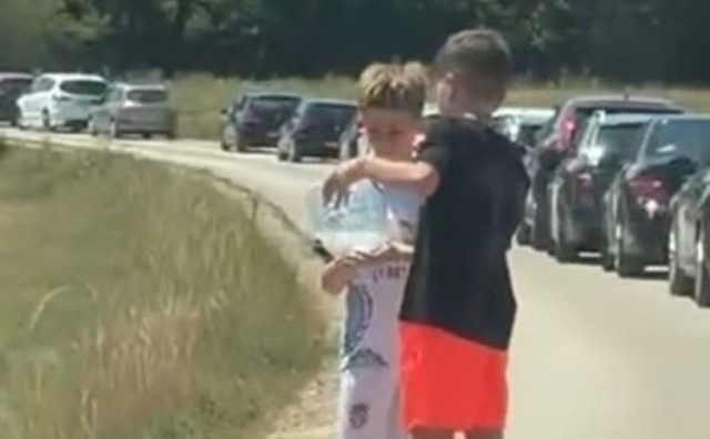 Dječaci dijelili vodu putnicima koji su čekali u koloni na granici u Vinjanima Gornjim